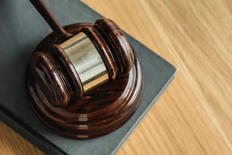 Close-up of a judge’s gavel resting on a law book on a wooden desk
