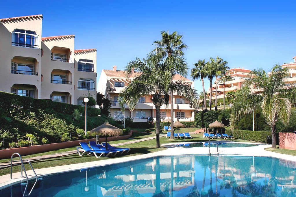 Outdoor swimming pool with sun loungers and palm trees in a Spanish apartment resort complex in Málaga/Fuengirola, Spain