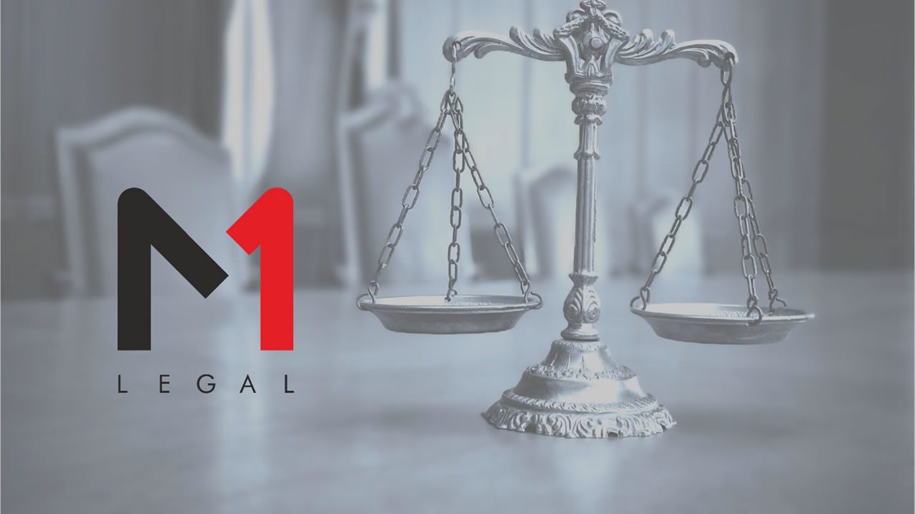 M1 Legal logo beside a silver balance scales statue on a blurred office background