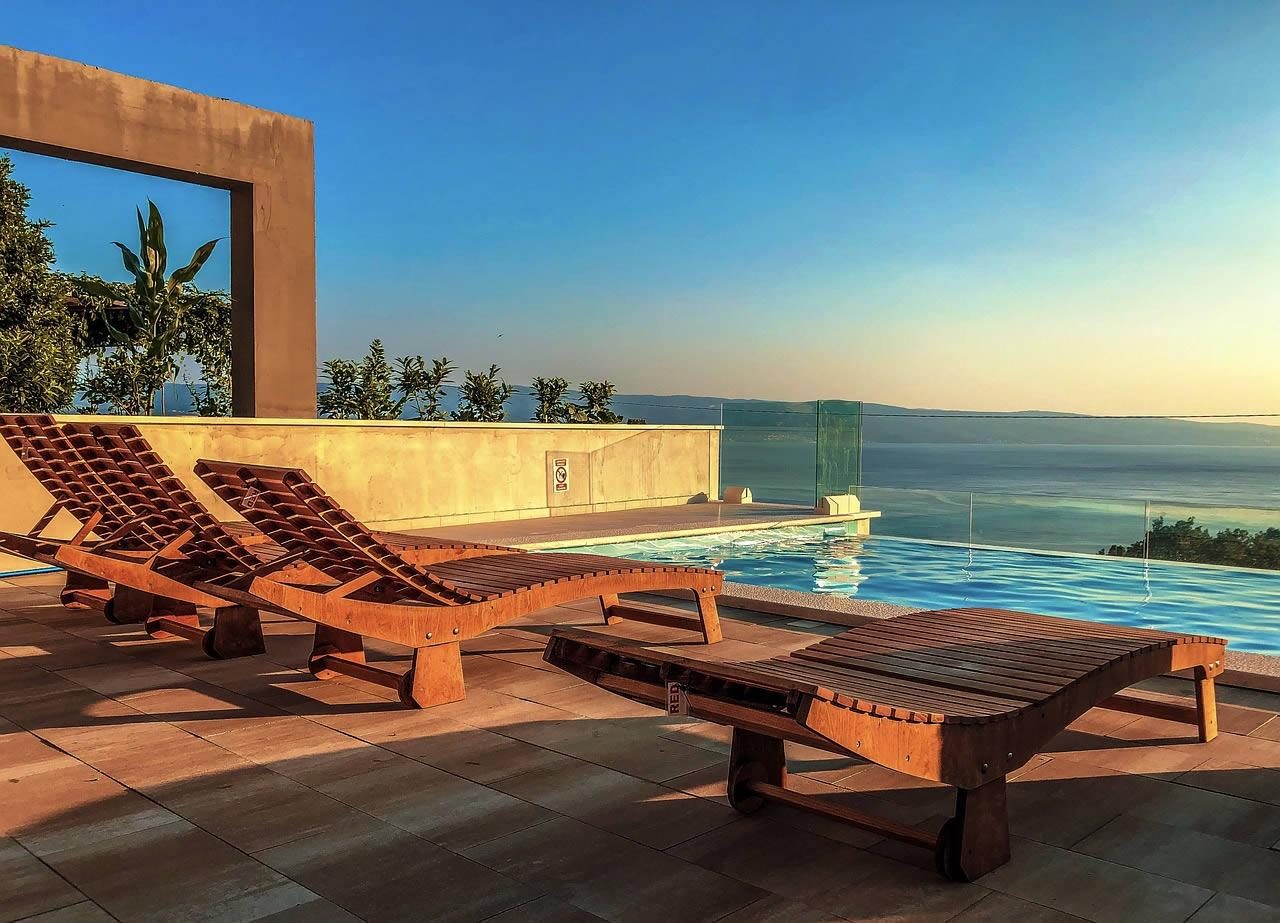 Sun loungers beside an infinity pool overlooking the sea at sunset in Spain