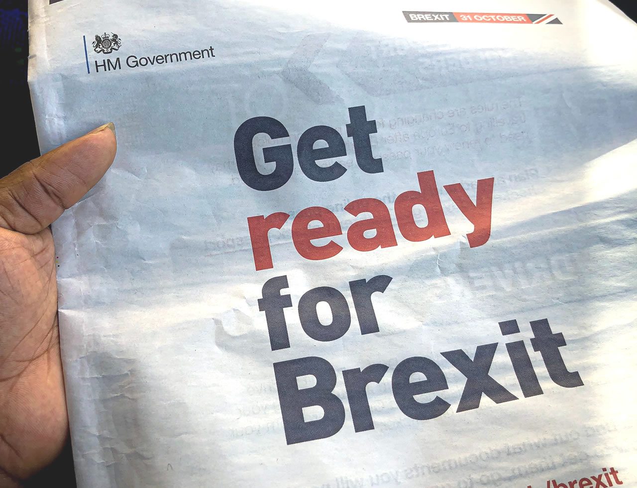 Hand holding an HM Government leaflet saying Get ready for Brexit with a Brexit 31 October banner at the top