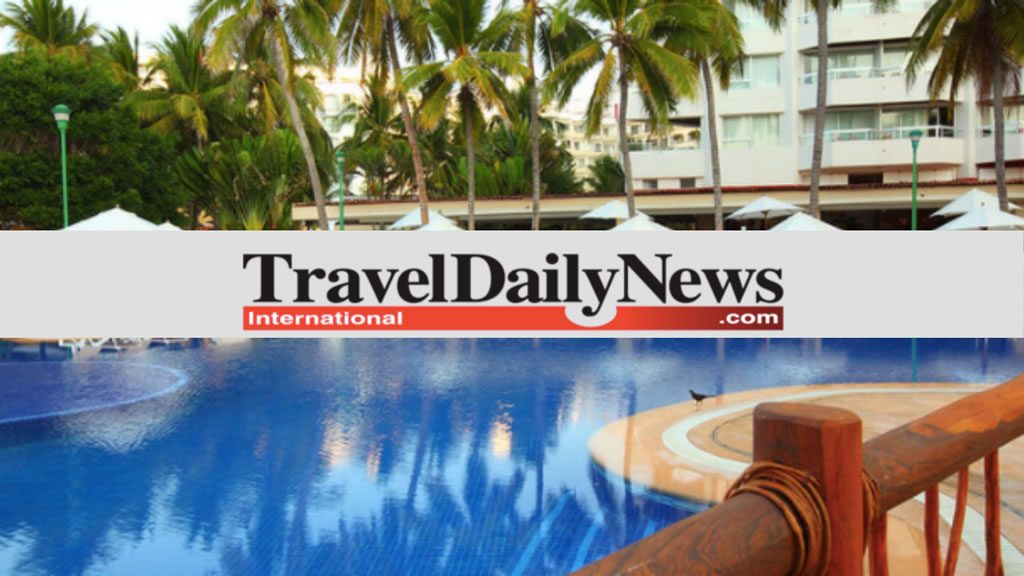 Swimming pool at a tropical resort with palm trees and a hotel building in the background, overlaid with “Travel Daily News” text