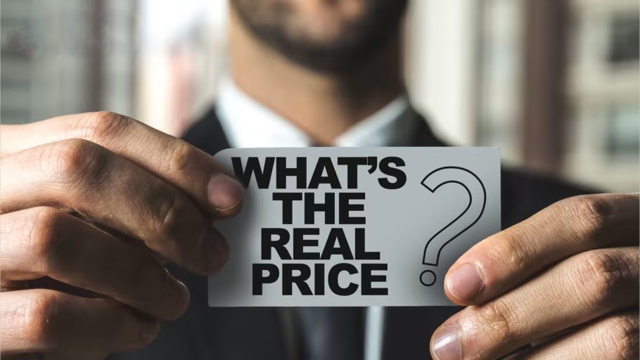 Person in a suit holding a card that reads “WHAT’S THE REAL PRICE” with a question mark icon