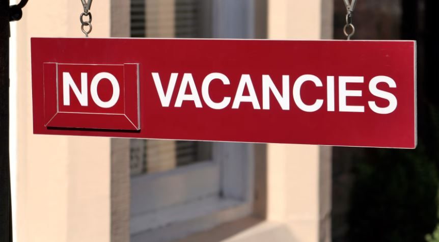 Red hanging sign reading “NO VACANCIES”, symbolising timeshare peak season availability problems