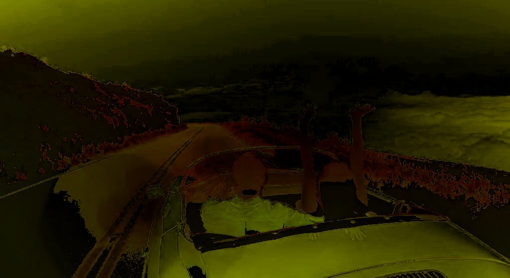 View from a car driving along a rural road under dark, stormy skies with trees lining the roadside