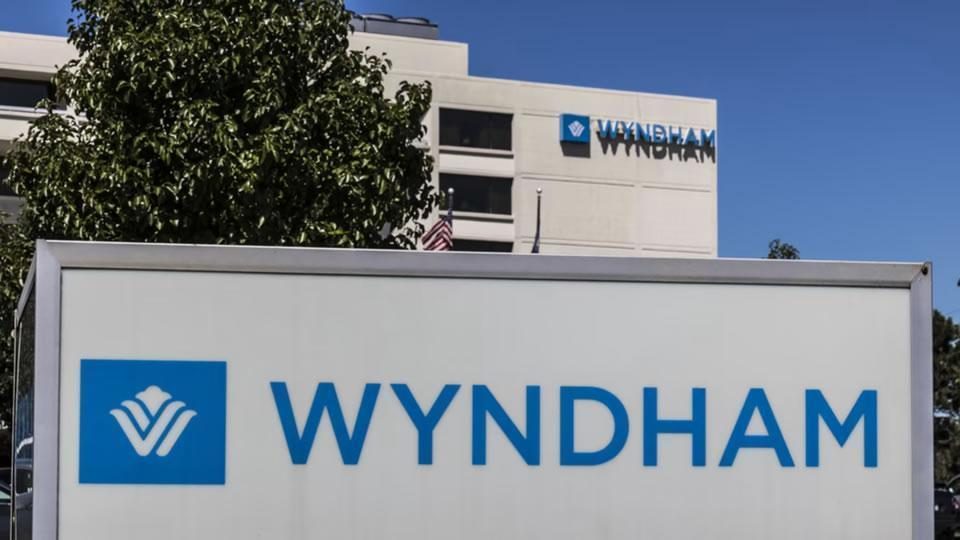 Wyndham hotel building with large Wyndham sign and logo in the foreground against a blue sky