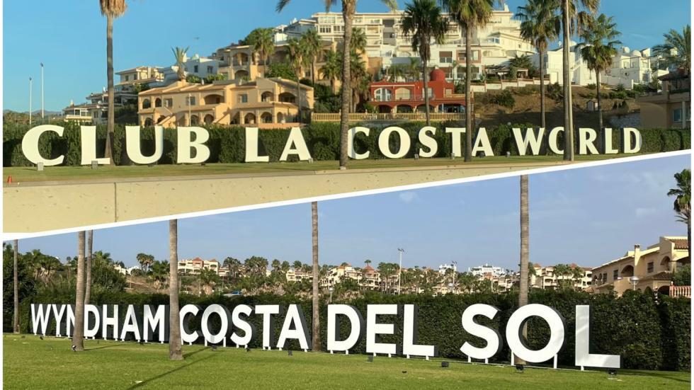 Sign reading “CLUB LA COSTA WORLD” and “WYNDHAM COSTA DEL SOL” in front of a hillside resort with palm trees and apartments under a clear blue sky