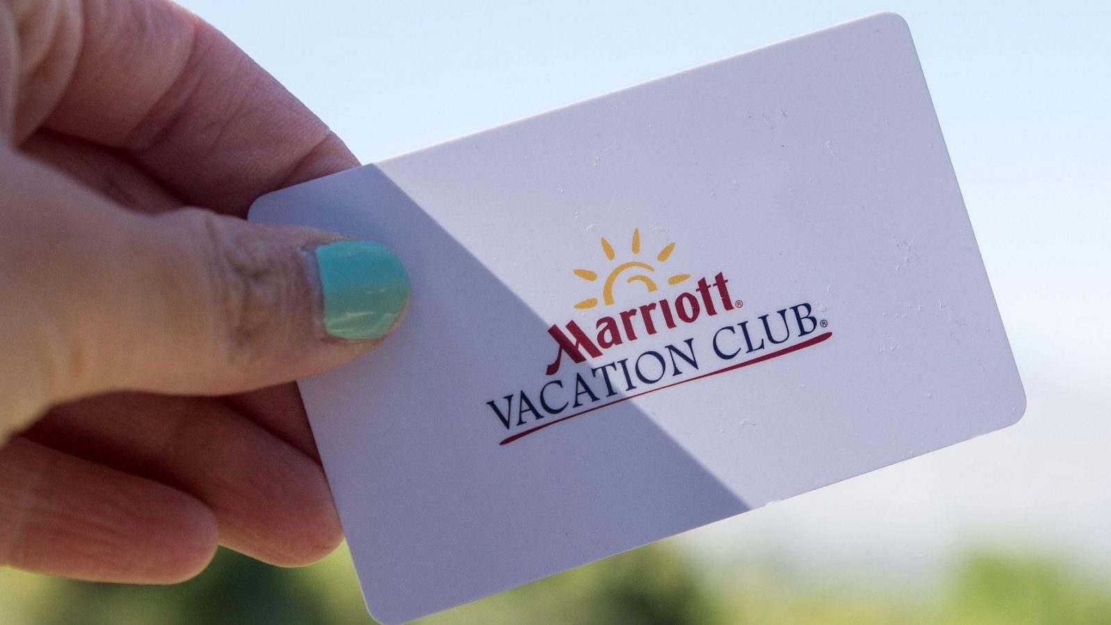 Hand holding a Marriott Vacation Club membership card against a blurred outdoor background
