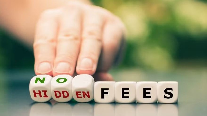 Hand sliding letter blocks that read “NO HIDDEN FEES” on a table, with a blurred green background