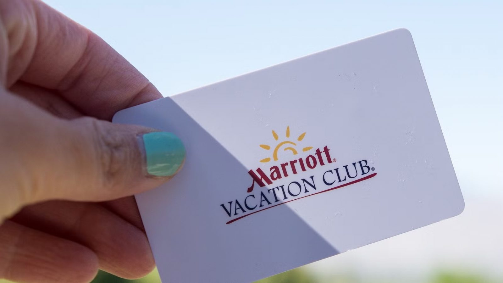 Hand holding a Marriott Vacation Club membership card against a bright sky background