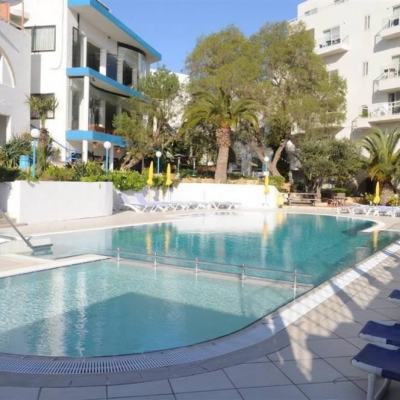 Outdoor swimming pool with sun loungers and parasols in a white apartment complex courtyard at Salina Wharf, Malta
