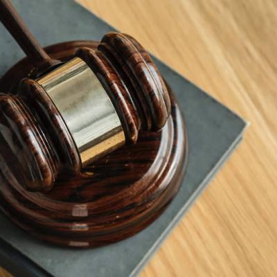 Close-up of a judge’s gavel resting on a law book on a wooden desk