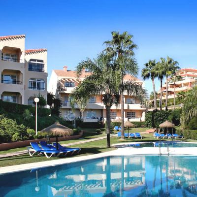 Outdoor swimming pool with sun loungers and palm trees in a Spanish apartment resort complex in Málaga/Fuengirola, Spain