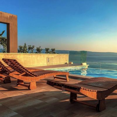 Sun loungers beside an infinity pool overlooking the sea at sunset in Spain