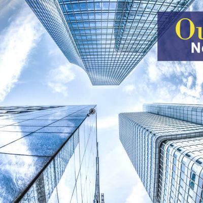 Upward view between modern glass skyscrapers against a blue sky, with the text “Our Story New Year 2019”