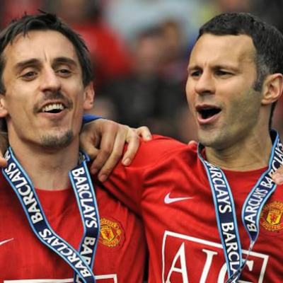 Two Manchester United footballers in red shirts wearing Barclays medals, celebrating with arms around each other on the pitch