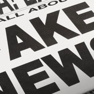 Close-up of a newspaper with the headline “FAKE NEWS!” in bold black letters and “EXTRA! EXTRA! READ ALL ABOUT” above it
