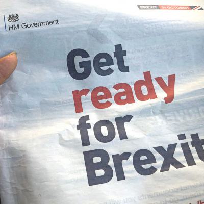 Hand holding an HM Government leaflet saying Get ready for Brexit with a Brexit 31 October banner at the top