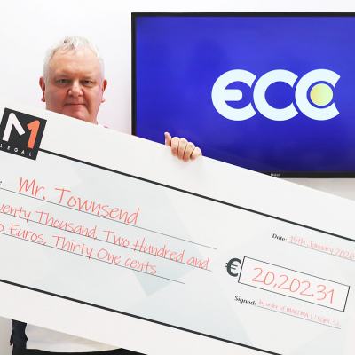 Man holding an oversized cheque for €20,202.31 made out to Mr Townsend, with M1 Legal branding and a screen behind displaying the ECC logo