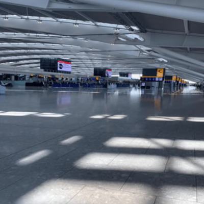 Empty airport terminal with closed check-in desks and digital flight information screens during lockdown