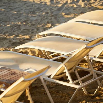 Empty sun loungers lined up on a sandy beach in warm sunlight