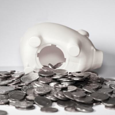 Overturned white piggy bank with coins spilled out on a grey surface, illustrating Club La Costa 2021 maintenance fees concerns during Covid