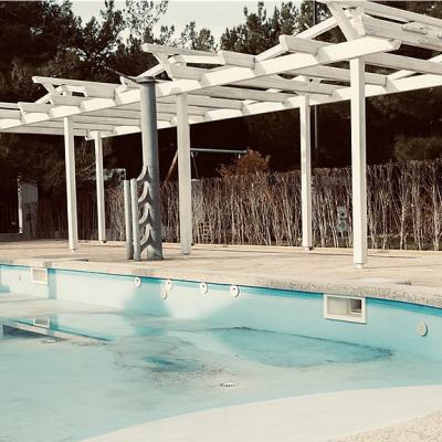 Empty outdoor swimming pool beside a pergola walkway and closed gate at a quiet resort, suggesting timeshare resort facilities being reduced