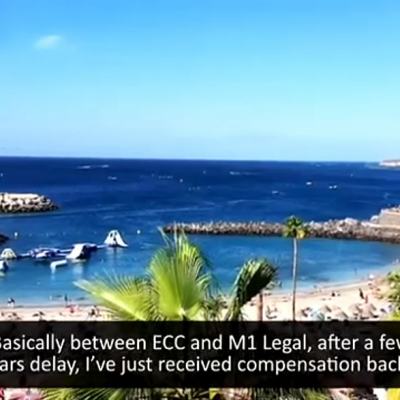 Beach and marina with palm trees, overlaid with a small video call headshot and on-screen captions mentioning ECC and M1 Legal.