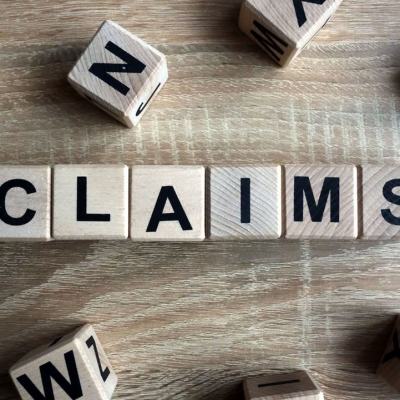 Wooden letter blocks on a table spelling CLAIMS, with scattered cubes around them, illustrating a timeshare compensation calculator to calculate timeshare claim value in minutes