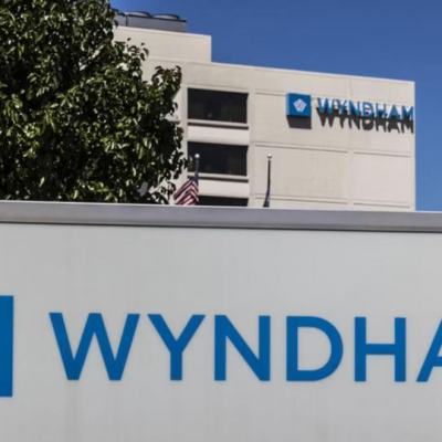 Wyndham hotel building with large Wyndham sign and logo in the foreground against a blue sky