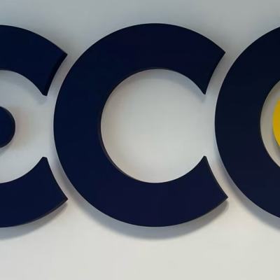 Close-up of the ECC logo in dark blue lettering with a yellow circle on a white wall