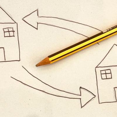 Pencil beside a sketch of two houses with arrows pointing between them, illustrating a timeshare exchange concept