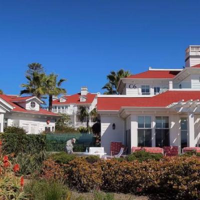 Holiday resort buildings with red roofs and white cladding, palm trees and landscaped gardens under a clear blue sky
