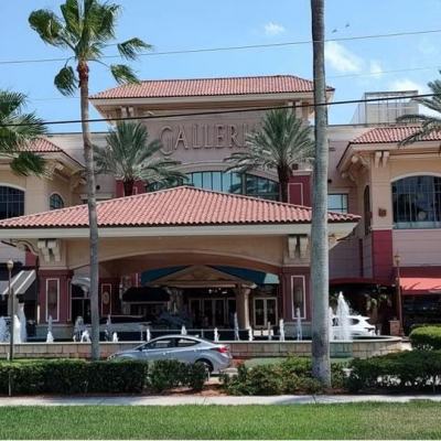 Exterior of The Galleria mall in Fort Lauderdale, with palm trees, fountains and the “GALLERIA” sign above the entrance