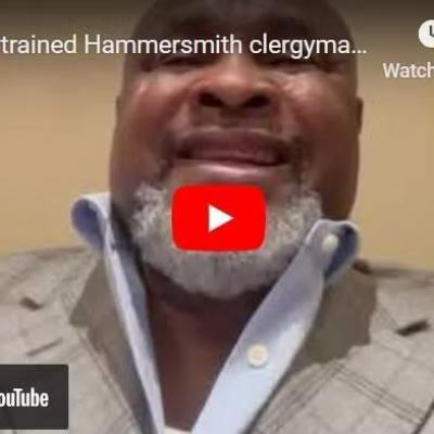 Close-up of a man in a checked blazer and open-collar shirt on a YouTube video thumbnail, with a red play button overlay and TAC icon in the corner