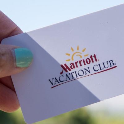 Hand holding a Marriott Vacation Club membership card against a blurred outdoor background