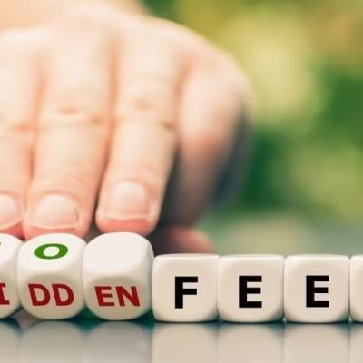 Hand sliding letter blocks that read “NO HIDDEN FEES” on a table, with a blurred green background