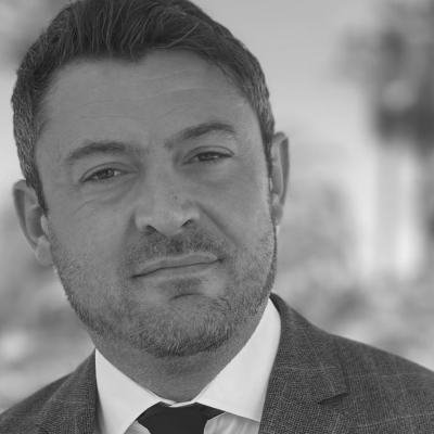 Black-and-white head-and-shoulders portrait of European Consumer Claims CEO Greg Wilson in a suit and tie with a blurred office background